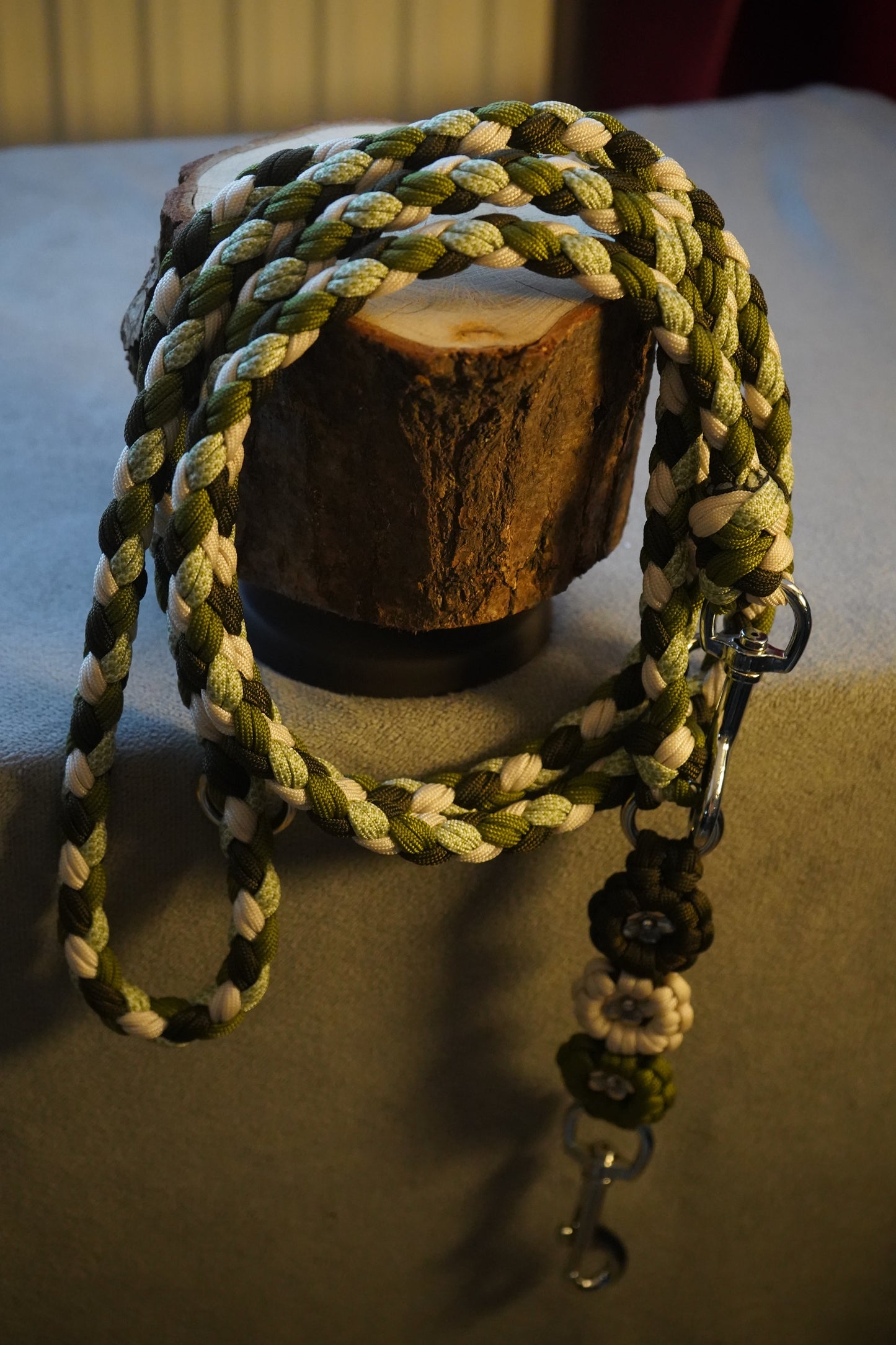 Paracord Hundeleine handgefertigt aus robustem Material in Grün-Beige-Tönen, präsentiert auf Holz – verstellbare, pflegeleichte Leine von Pama.