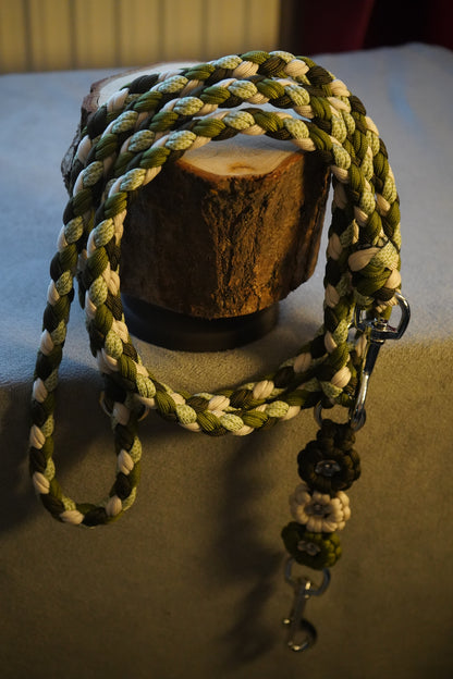 Paracord Hundeleine handgefertigt aus robustem Material in Grün-Beige-Tönen, präsentiert auf Holz – verstellbare, pflegeleichte Leine von Pama.